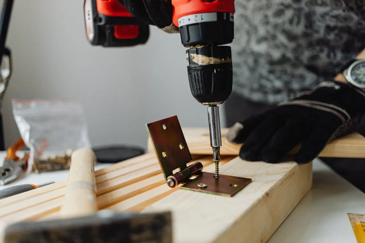 A hinge being fastened to a wooden cabinet door