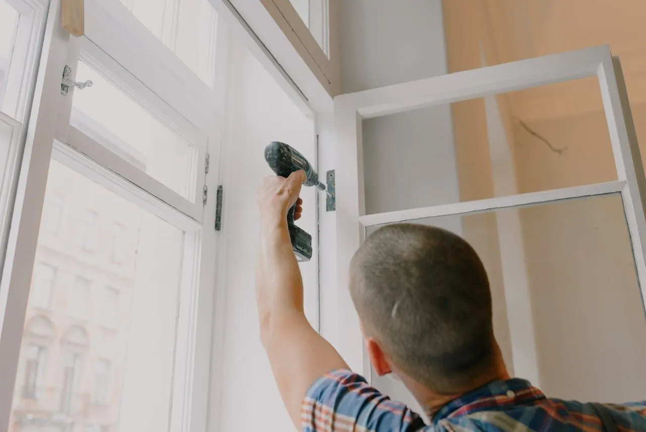 A worker adjusting the hardware on a window frame